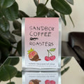Sandbox Coffee Roasters packaging with a pink label against a neutral background