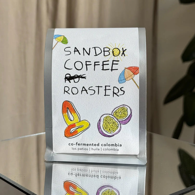 Co-fermented Colombia specialty coffee bag with fruit illustrations and playful handwritten text.