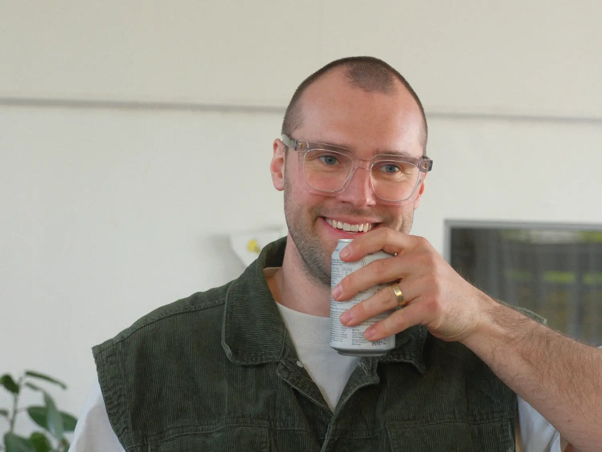 Man holding a can of soda indoors with a neutral background