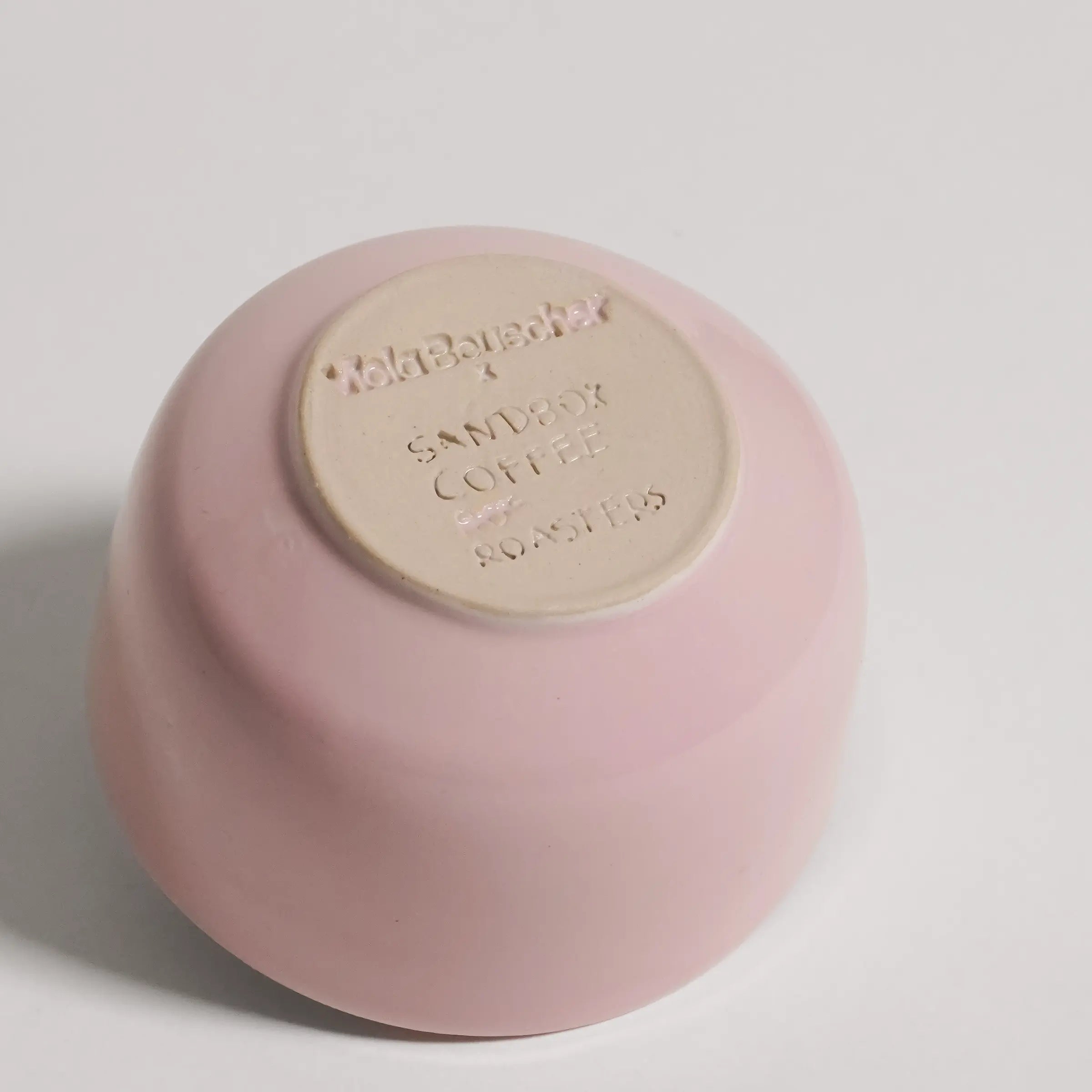 Pink ceramic cup from the bottom on a light gray background