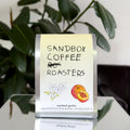 Sandbox Coffee Roasters coffee bag with a plant in the background
